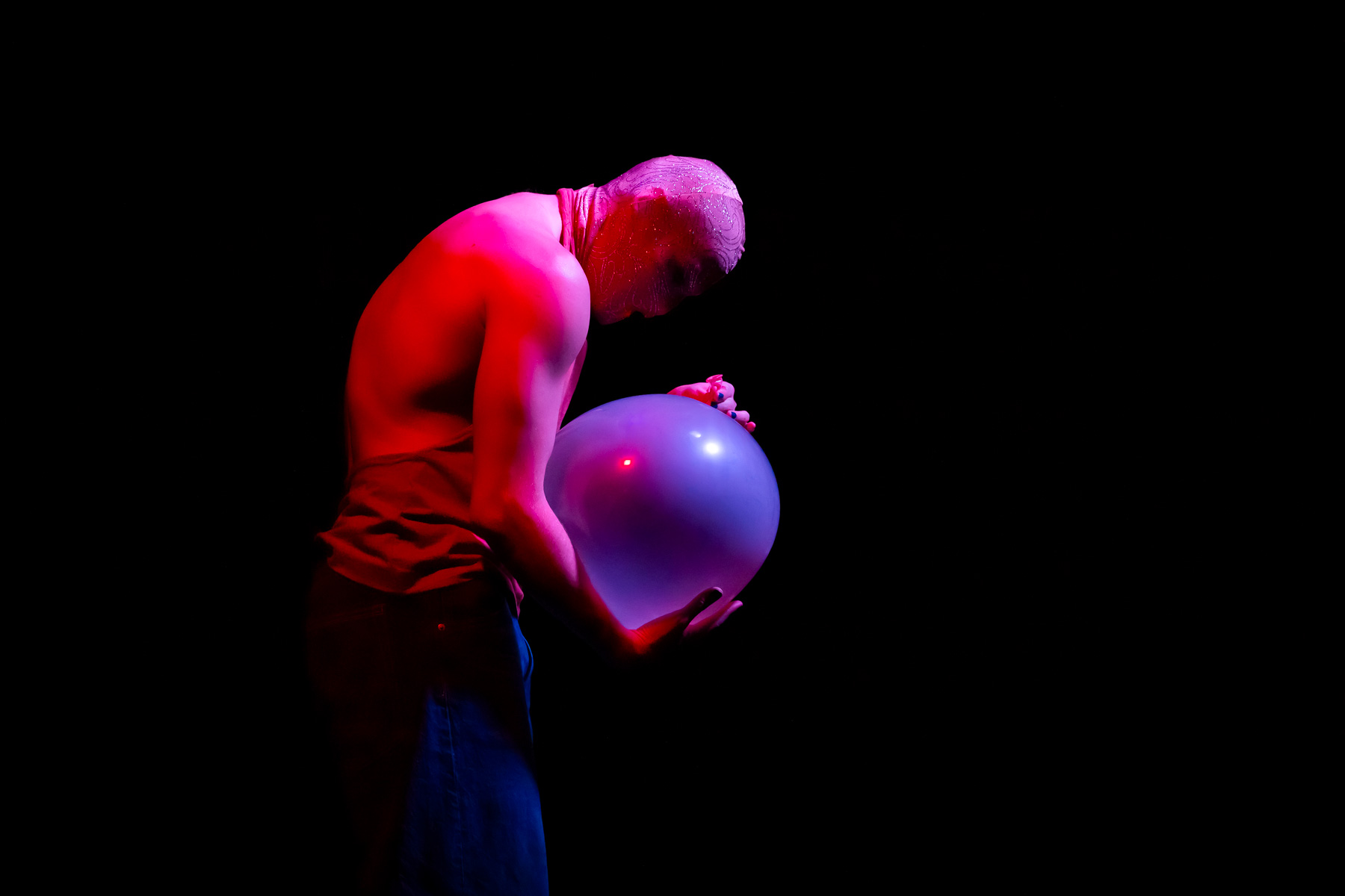 Figure poétique d'un homme enceint avec un ballon de baudruche, lumière rose et bleue.