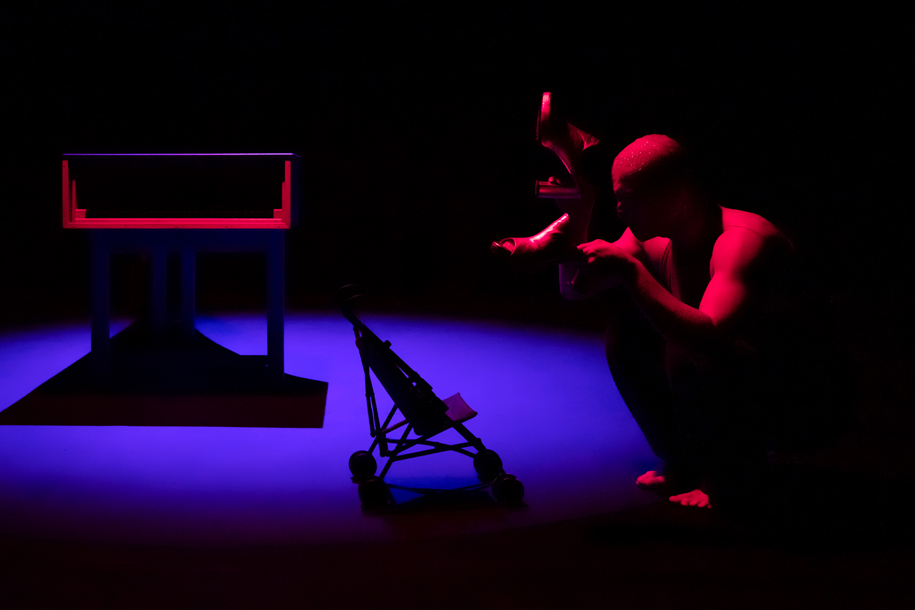 Homme cagoulé dans une ambiance lumineuse saturée de bleu et de rouge.