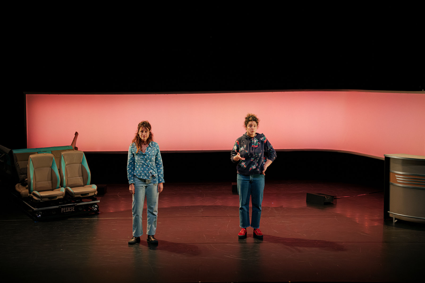 Deux femmes sur une scène de théâtre devant un cyclorama panoramique ambré.
